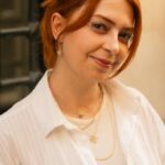 A stylish portrait of a woman with red hair set against an urban Istanbul backdrop.